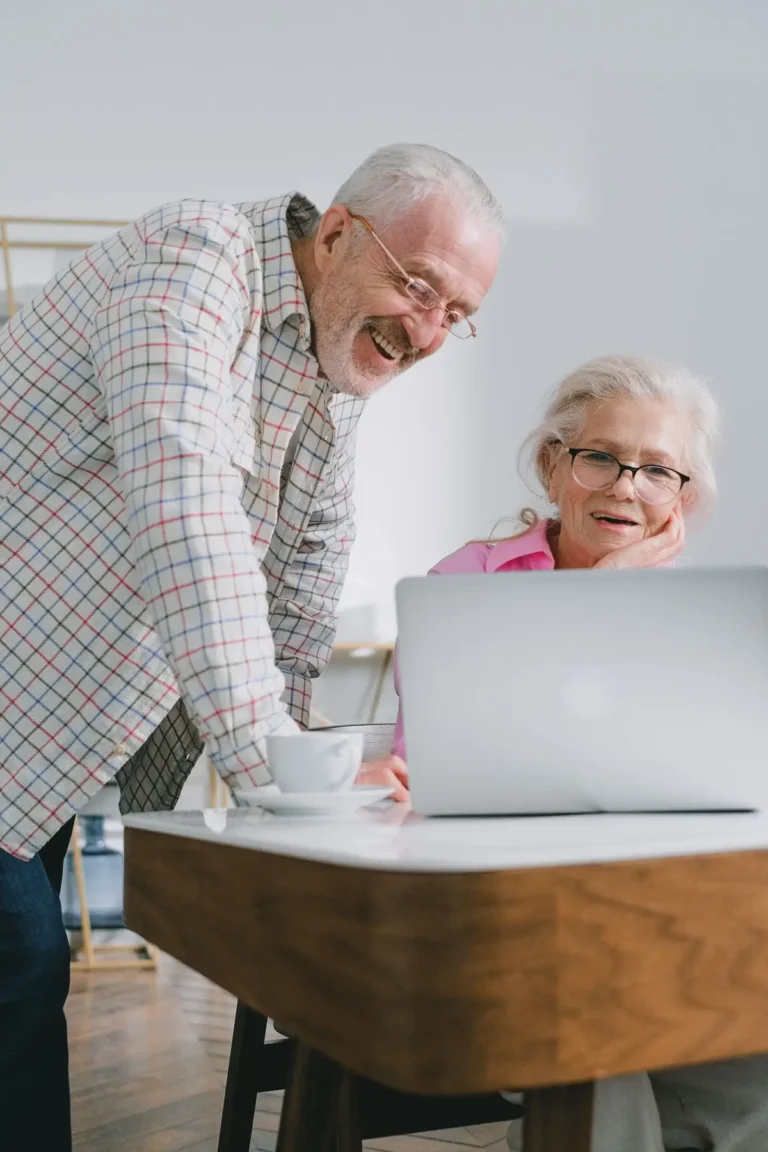 Couple de seniors souriant devant un ordinateur portable