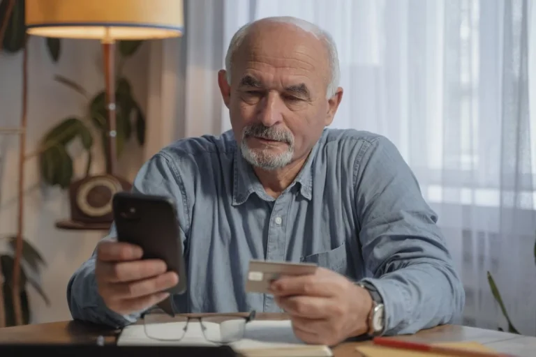 Homme senior tenant une carte bancaire et son téléphone
