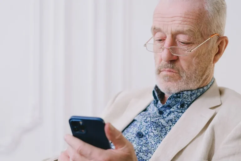 Homme senior consultant son smartphone chez lui