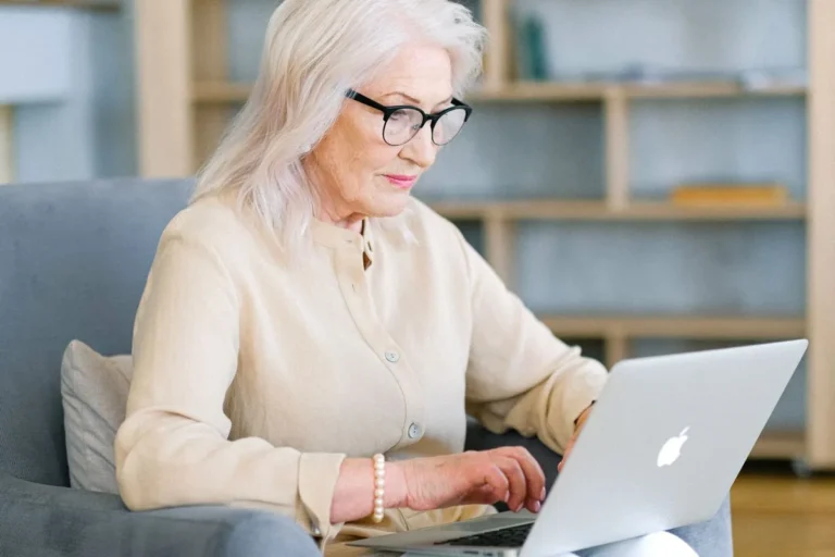 Femme senior devant son ordinateur portable dans son salon